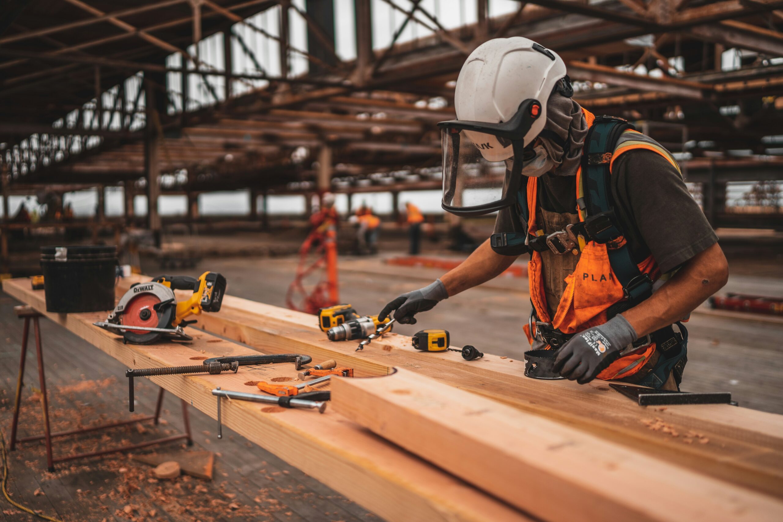 A worker at a timber yard wearing a hard hat